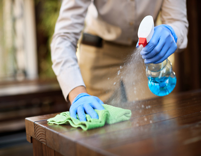 close up of waitress disinfecting tables at outdoor cafe.