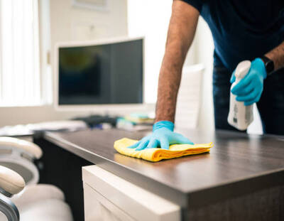man disinfecting an office desk